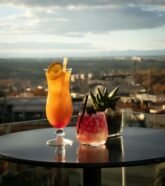 Vibrant cocktails on a rooftop terrace in Madrid with stunning city views.