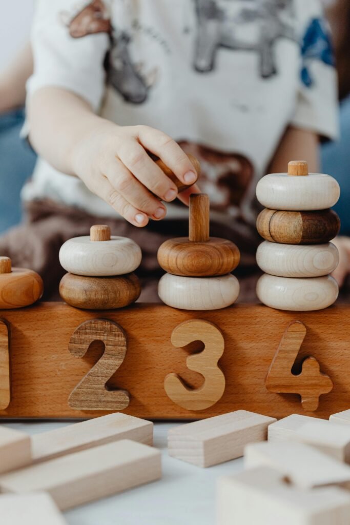 pexels photo 7269671 7269671 A child interacts with educational wooden number blocks, enhancing cognitive skills.