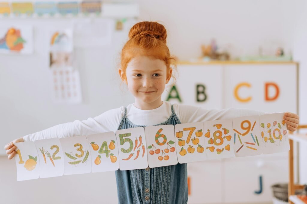 pexels photo 8923566 8923566 Young girl showcasing number cards in a vibrant classroom setting.